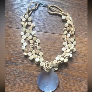 multi-strand beaded statement necklace with a large, iridescent pendant